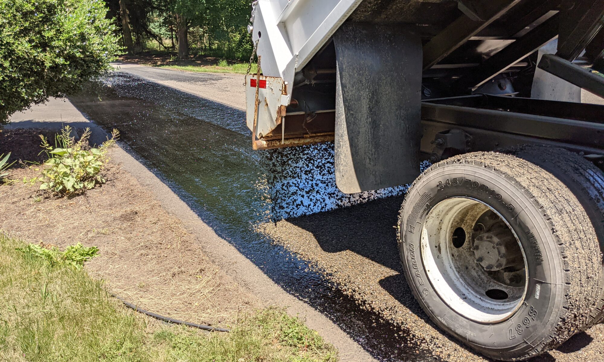 Chip seal rock being applied to fresh chip oil